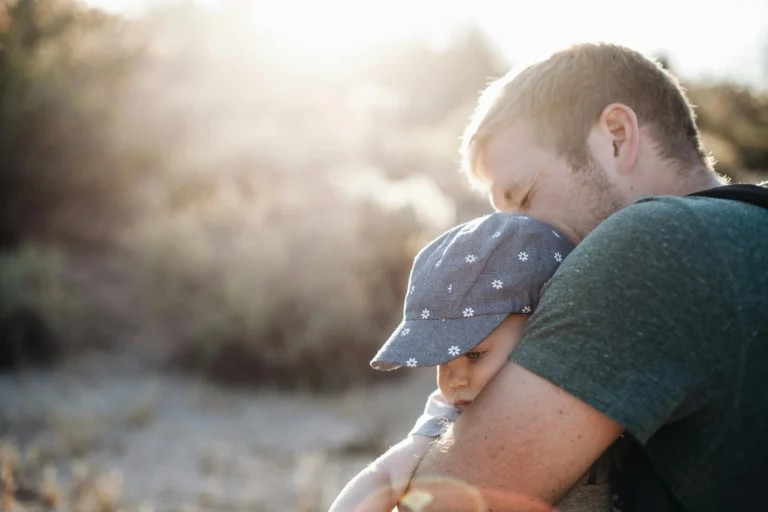 A young father holding his child with a sunlit background
