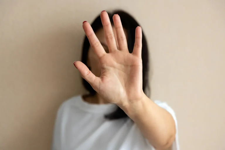 A young women putting her hand up to stop a person from that persons perspective