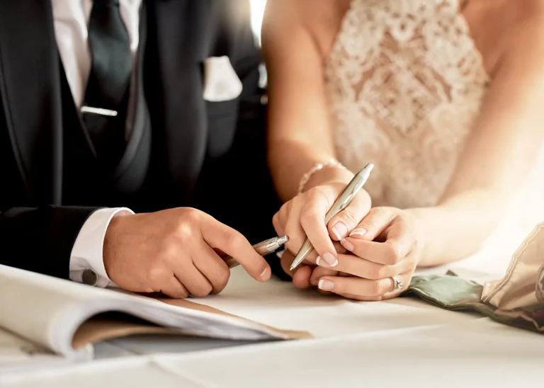 A newly married couple signing their marriage documents