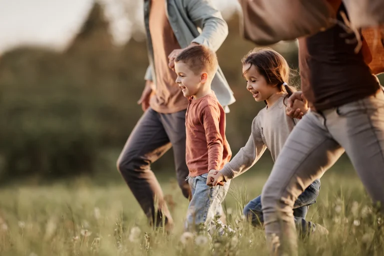 A happy family running across a grass covered field
